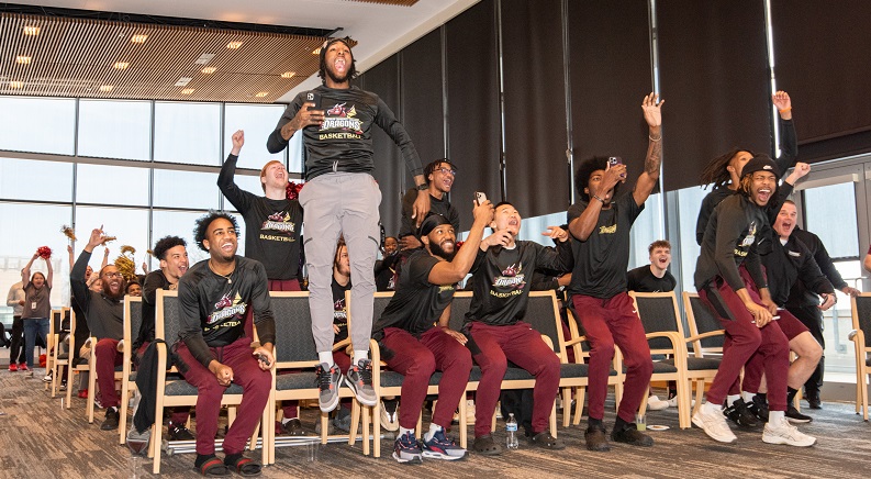 Basketball players celebrating together in an auditorium