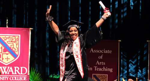 student raising arms in triumph at commencement