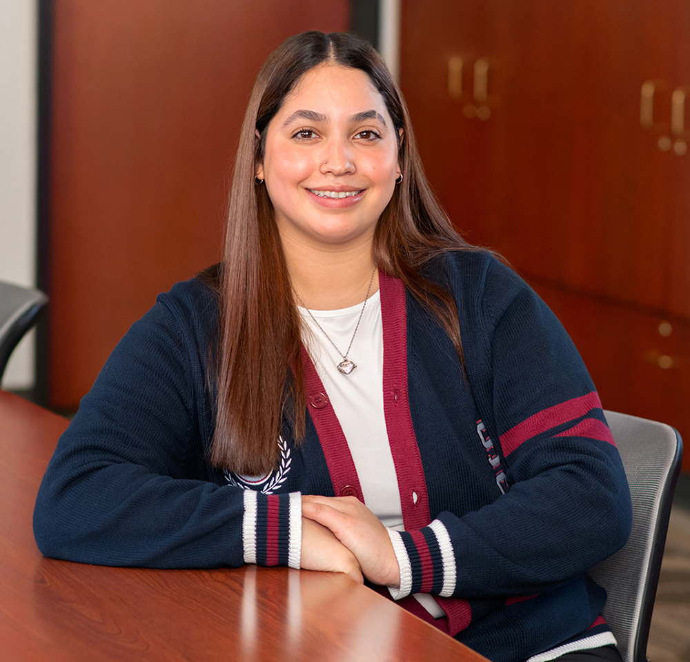 A profile photo of Deja Moorman wearing a blue and maroon cardigan sweater over a white shirt.