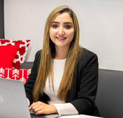 A headshot of Miriam Kamran sitting at a computer.