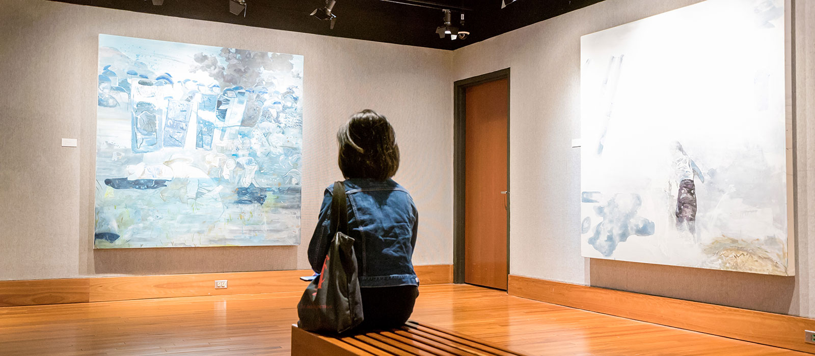 Photos of a person looking at the paintings on the gallery wall.