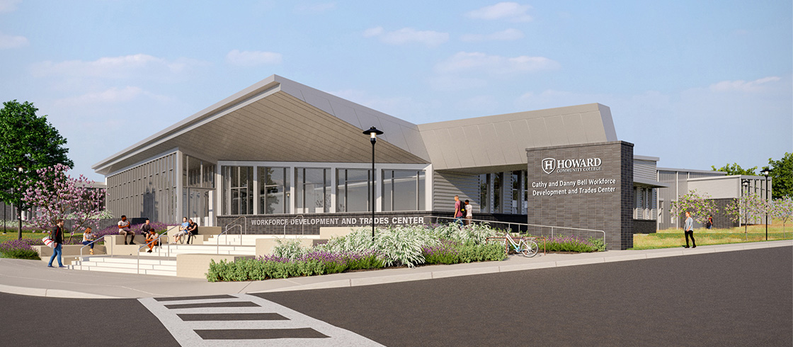 Exterior of the Cathy and Danny Bell Workforce Development and Trades Center at Howard Community College, showing a modern building with large windows, a sloped roof, and people outside.