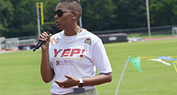 Dr Daria J Willis speaking into a microphone with a tshirt that says YEP!