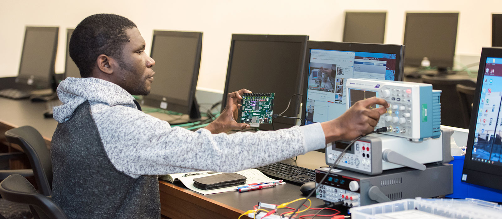 Student sitting in front of a computer using engineering equipment